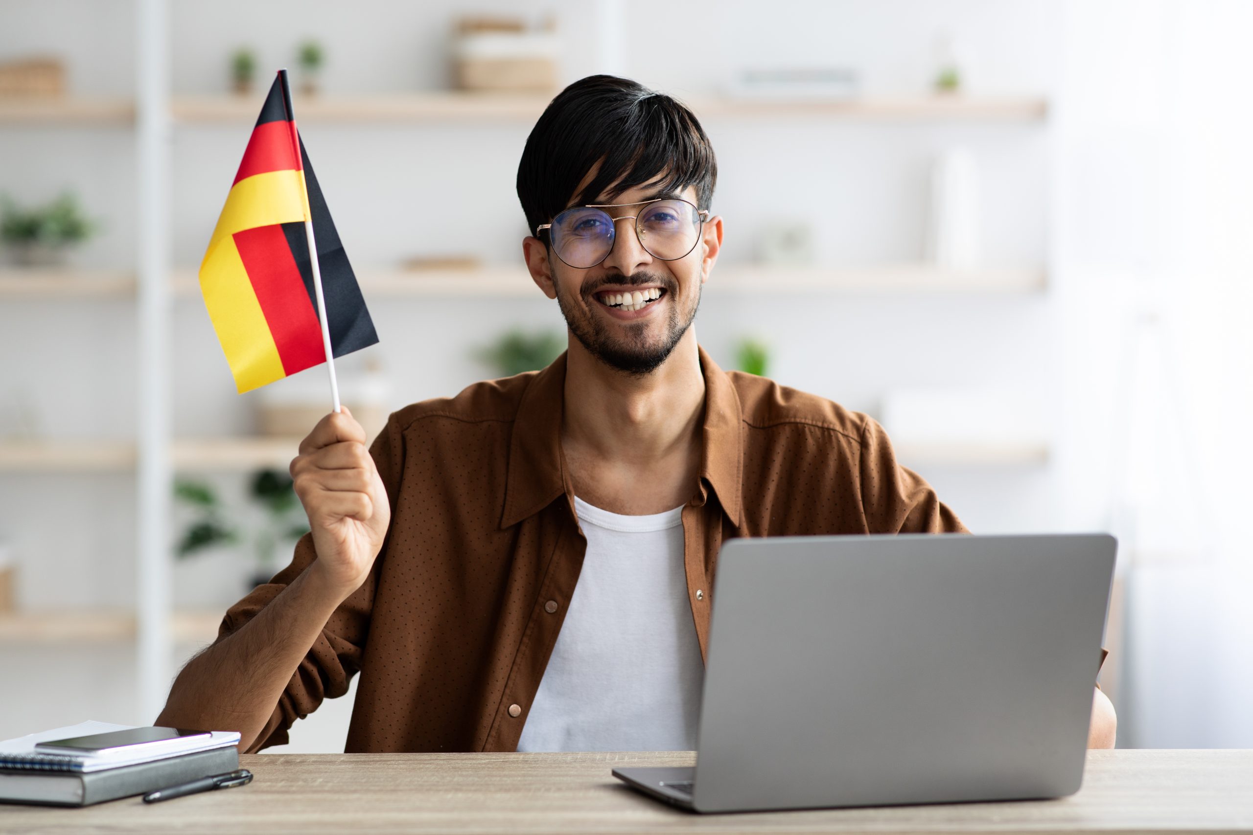 smiling indian guy student showing flag of germany 2021 11 03 19 49 10 utc scaled